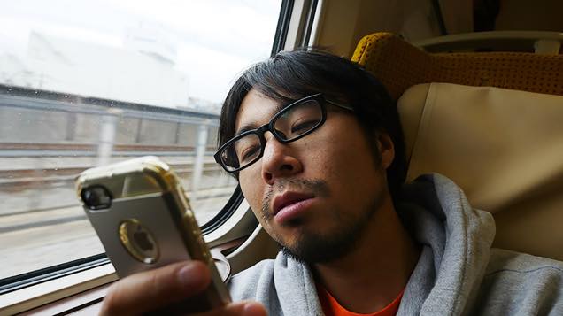 新幹線の座席で疲れた表情でスマホを眺める筆者